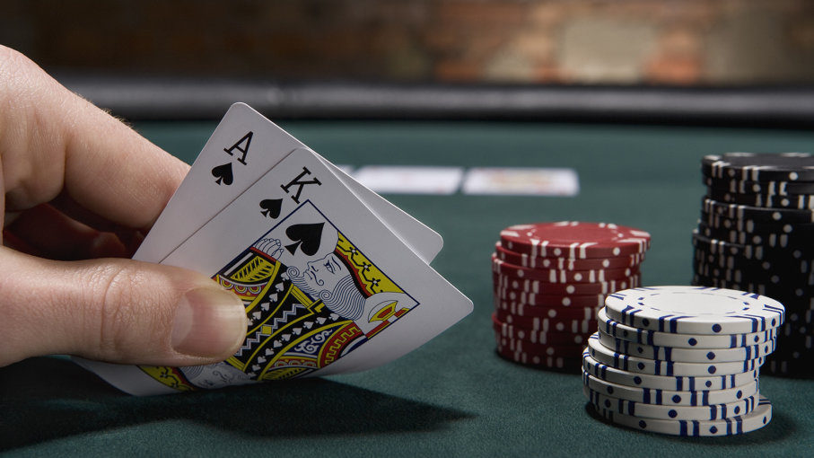 Hand som håller spelkort med spader ess och spader kung samt spelmarker